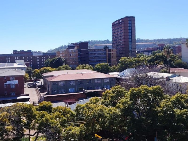 Elevated urban outlook showcasing surrounding apartment buildings, mature trees, and city infrastructure.
