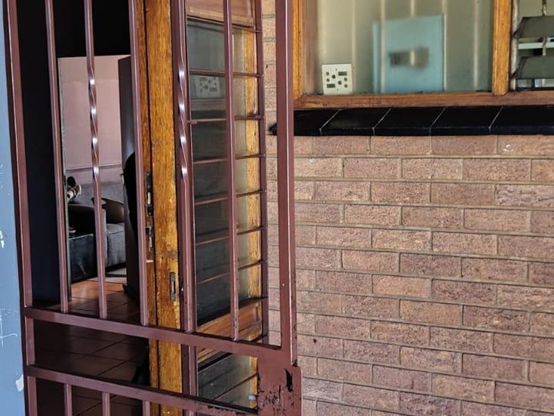 Entrance area featuring a brick facade, security gate, and tiled flooring, providing access to the interior of the apartment.