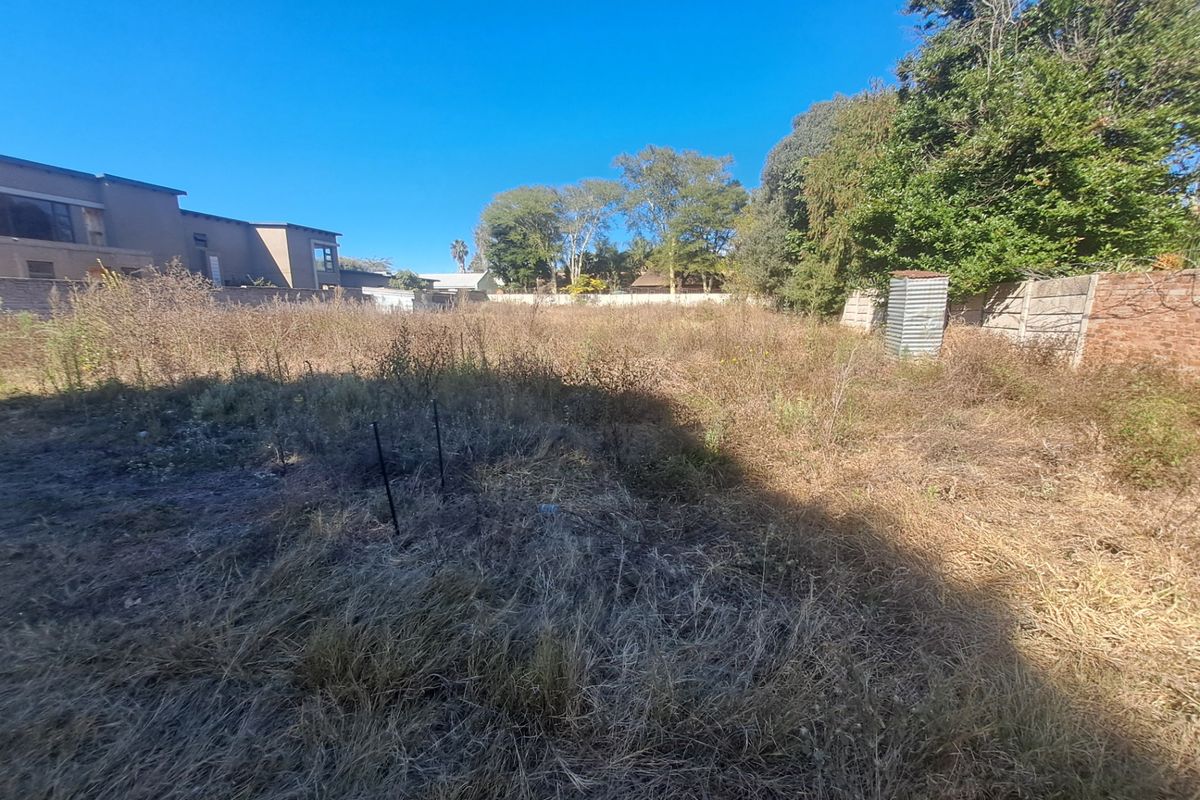 A vacant residential plot featuring overgrown vegetation, enclosed by perimeter boundary walls, offering a blank canvas for future development.