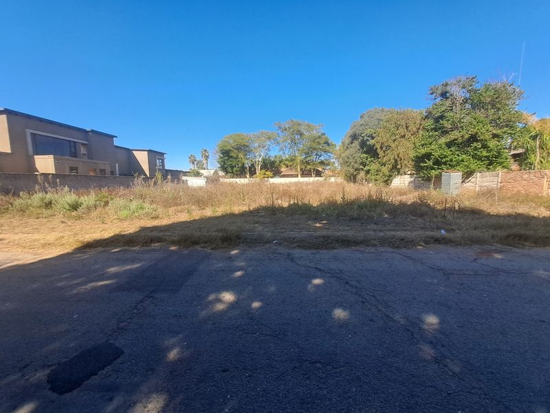 A vacant residential plot featuring level ground, perimeter walling, and established trees, offering a blank canvas for new construction in a developed neighborhood.