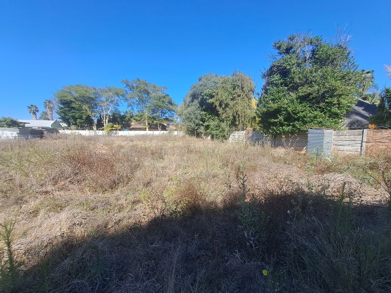 A vacant residential plot featuring overgrown grass and established perimeter boundary walls, offering a blank canvas for future development.