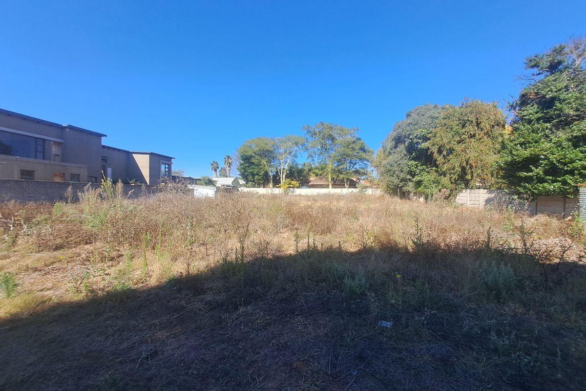A vacant residential plot featuring overgrown vegetation, enclosed by perimeter boundary walls, offering a blank canvas for future development.