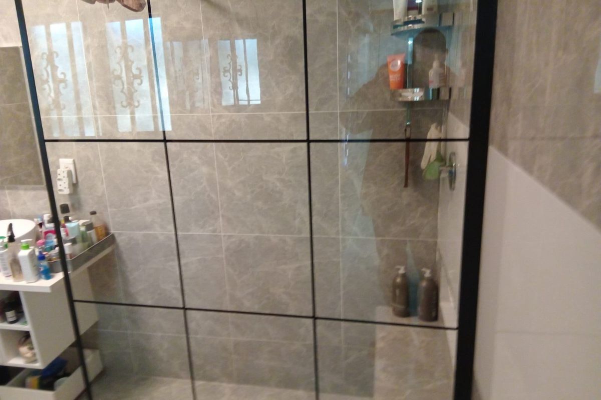 Modern bathroom featuring a walk-in shower with a black-framed glass screen and contemporary marble-look wall tiling.