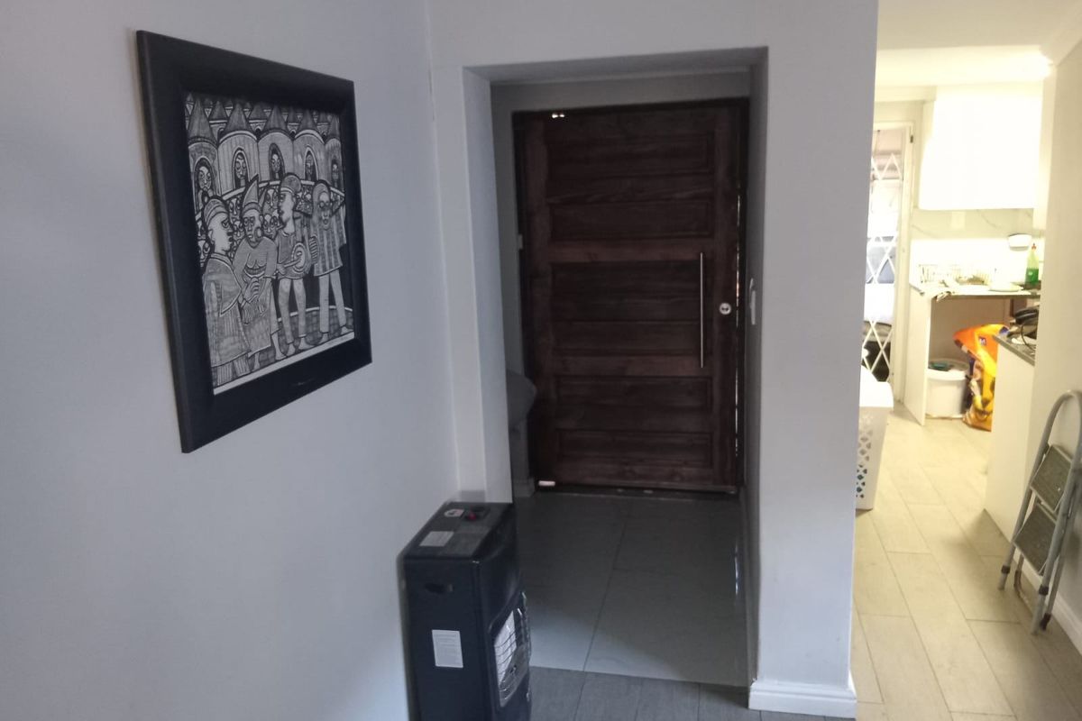 Entrance area featuring a solid wood front door and tiled flooring, leading into the adjacent living and kitchen spaces.