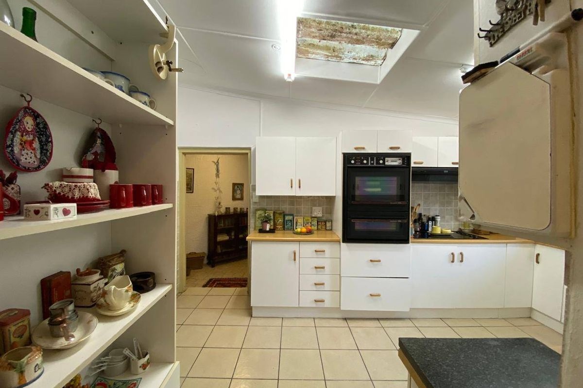 Functional kitchen featuring built-in double oven, electric hob, tiled flooring, and a skylight providing natural light.