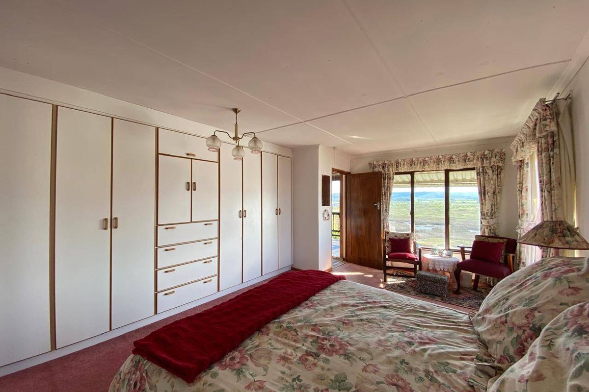 A spacious bedroom featuring extensive built-in cabinetry, carpeted flooring, and a large window offering scenic landscape views.
