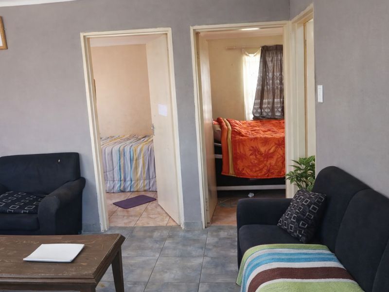 A view from the living area looking into two adjacent bedrooms, featuring tiled flooring and standard door frames.