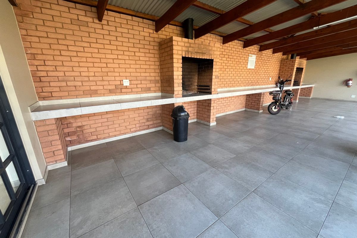 Covered outdoor patio area featuring a built-in brick braai, tiled countertop, and durable floor tiling, ideal for outdoor entertaining.