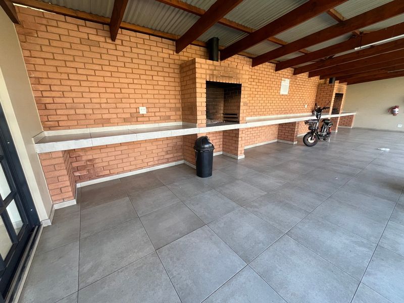 Covered outdoor patio area featuring a built-in brick braai, tiled countertop, and durable floor tiling, ideal for outdoor entertaining.