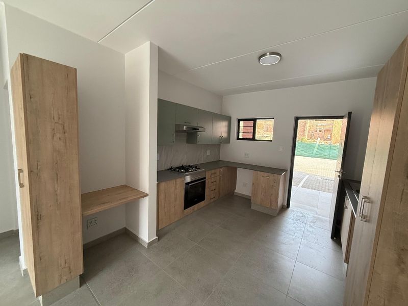Modern kitchen featuring wood-look cabinetry, built-in oven, gas hob, extractor fan, and tiled flooring with direct access to the exterior.