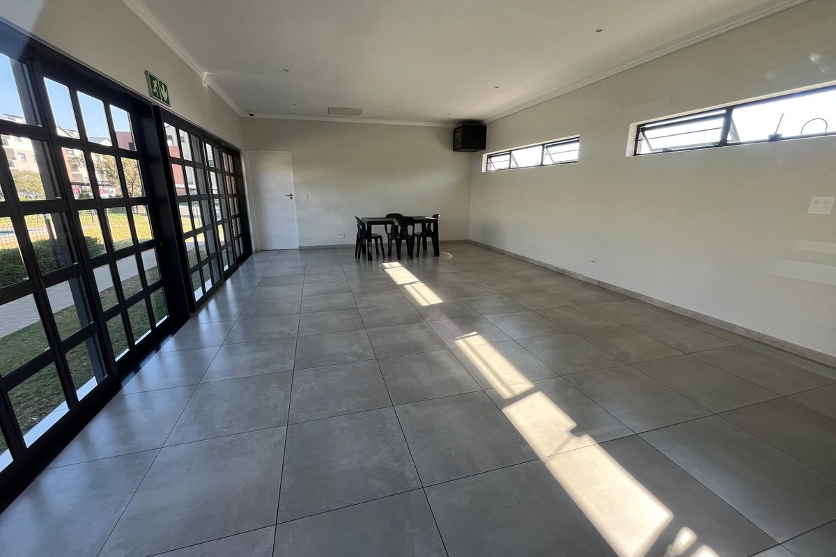 Spacious, open-plan living area featuring large glass sliding doors, neutral tiled flooring, and recessed lighting, offering a bright and versatile space.