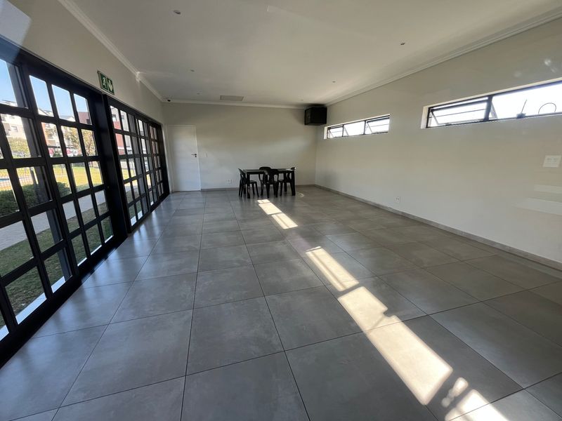 Spacious, open-plan living area featuring large glass sliding doors, neutral tiled flooring, and recessed lighting, offering a bright and versatile space.