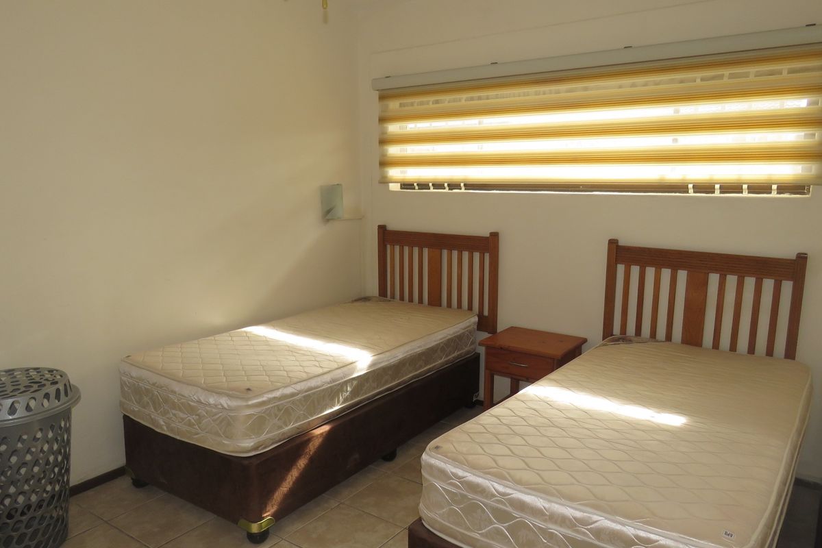 A bedroom featuring tiled flooring and a horizontal window fitted with a striped roller blind.