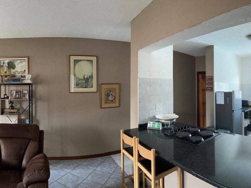 Open plan living and kitchen area featuring a breakfast bar with integrated electric hob and tiled flooring.