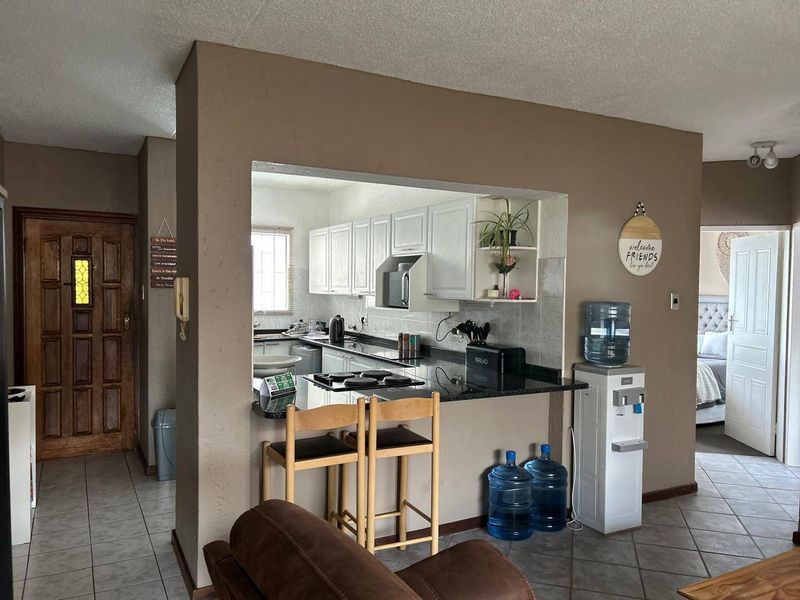 Open plan kitchen featuring granite countertops, white cabinetry, and a breakfast bar, seamlessly connecting to the living area.