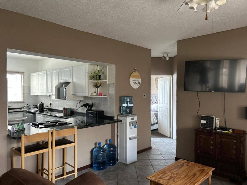 Open-plan living area featuring a kitchen with white cabinetry, granite countertops, and a breakfast bar, flowing into the adjacent living space.