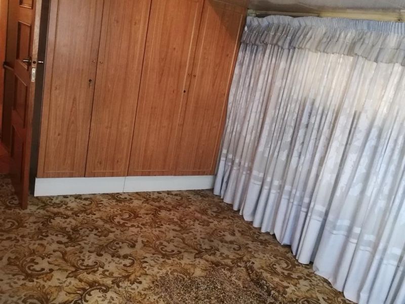 A bedroom featuring extensive built-in wooden cabinetry and patterned carpeting, offering significant storage space and a traditional layout.