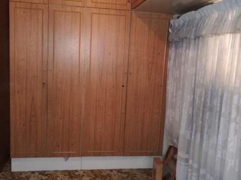 Bedroom featuring extensive floor-to-ceiling built-in wooden cabinetry and patterned carpet flooring.
