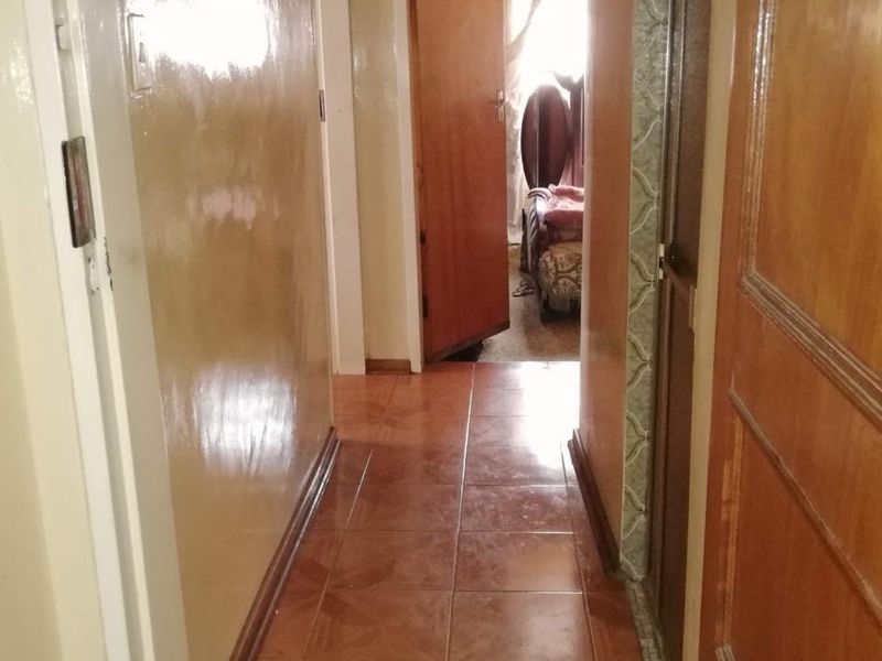 A narrow interior hallway featuring tiled flooring, wooden door frames, and access to adjacent rooms.