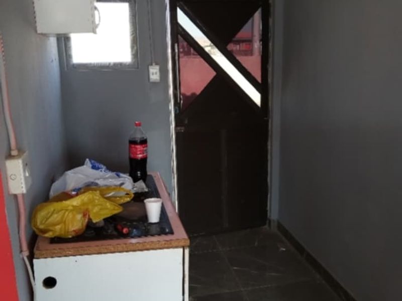 A small utility or scullery area featuring tiled flooring, basic cabinetry, and direct exterior access through a dark-framed door.
