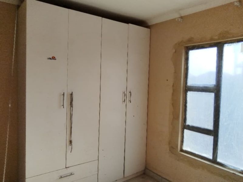 Bedroom featuring a built-in wardrobe and a window with unfinished plasterwork around the frame, requiring cosmetic repairs and painting.