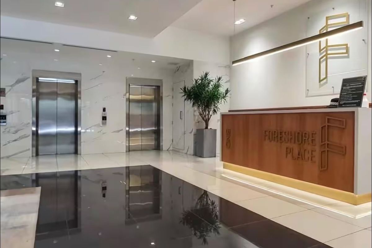 Modern apartment building lobby featuring a professional reception desk, polished tile flooring, and stainless steel elevator access.