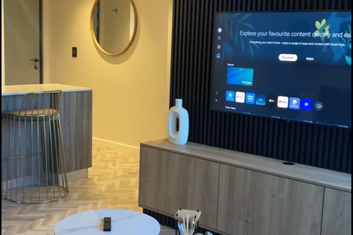 Modern living room featuring a stylish black slatted feature wall, herringbone flooring, and integrated cabinetry, creating a contemporary and sophisticated atmosphere.
