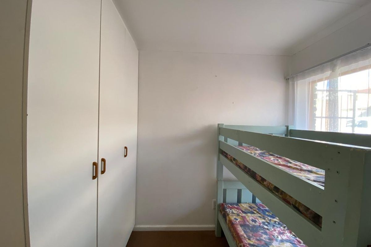A functional bedroom featuring built-in cupboards and natural light from the window.