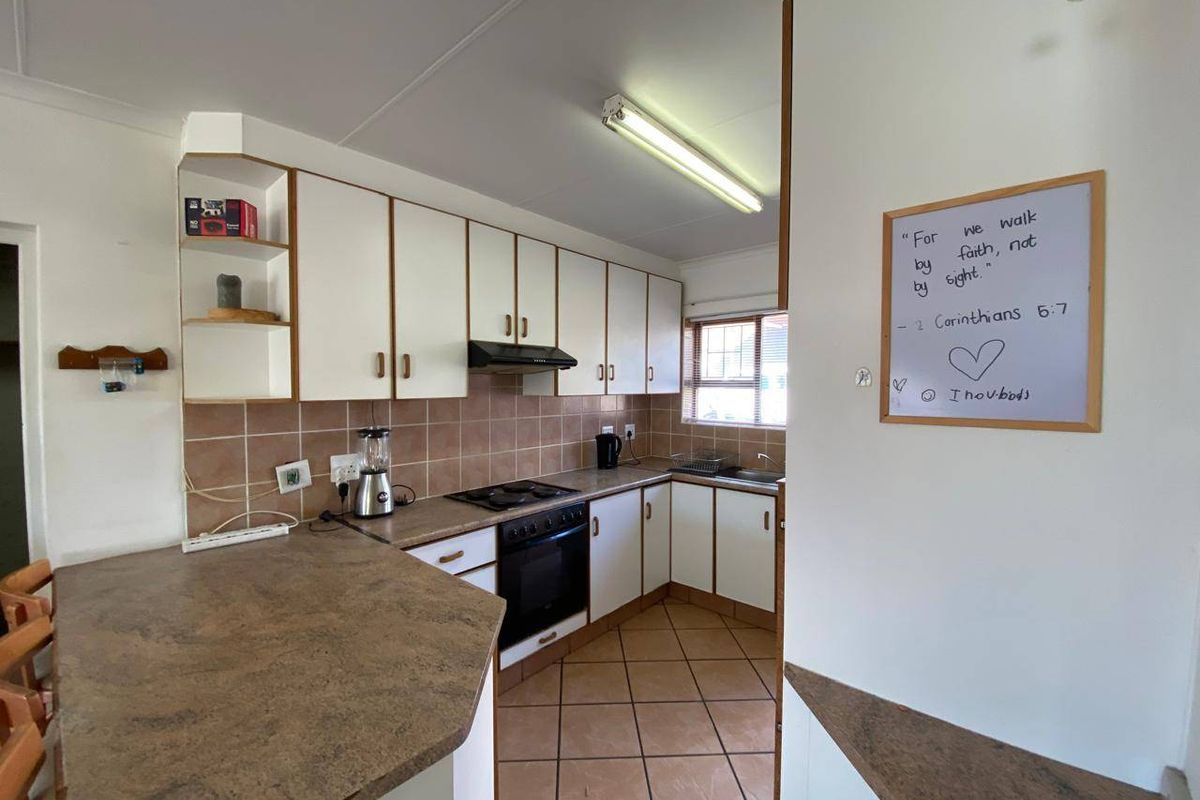 A functional kitchen featuring white cabinetry, laminate countertops, tiled splashback, and integrated appliances, offering a practical layout with ample storage space.