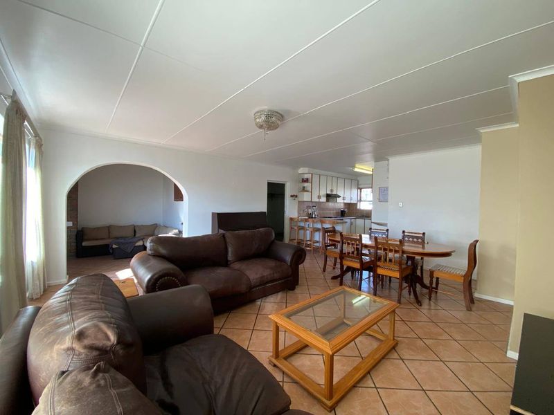 Spacious open-plan living and dining area featuring tiled flooring, an arched entryway, and a functional kitchen with built-in cabinetry and a breakfast bar.