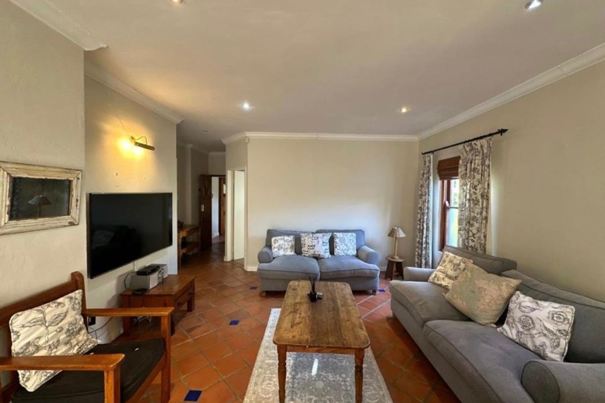 A comfortable living room featuring traditional terracotta floor tiles, recessed downlighting, and coved cornicing, providing a warm and inviting atmosphere.