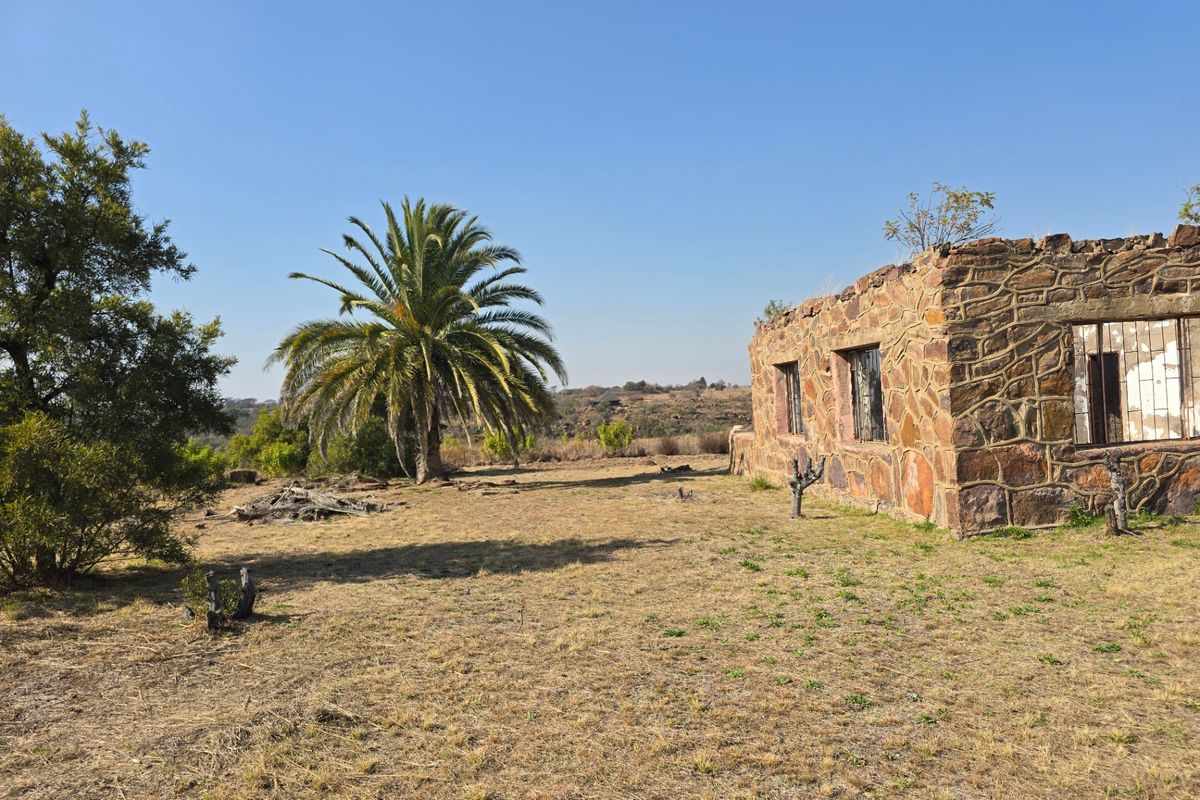 A view of a derelict stone structure on a vacant residential plot, featuring original stone walls and surrounding natural landscape.