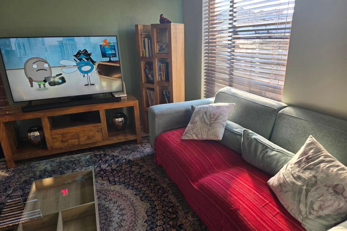 A cozy living room featuring a large window with fitted wooden blinds, providing natural light to the space.
