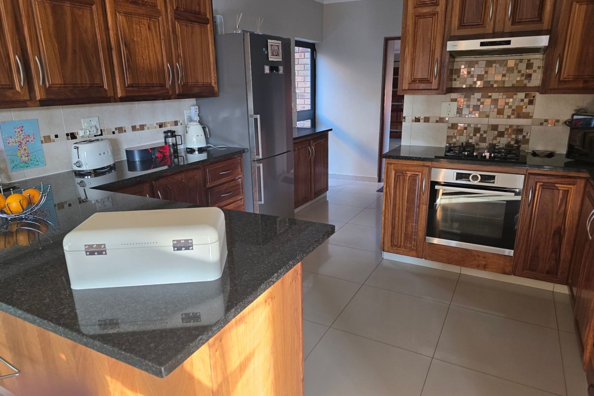 A functional kitchen featuring dark wood cabinetry, granite countertops, a built-in oven, gas hob, and a mosaic tile backsplash.