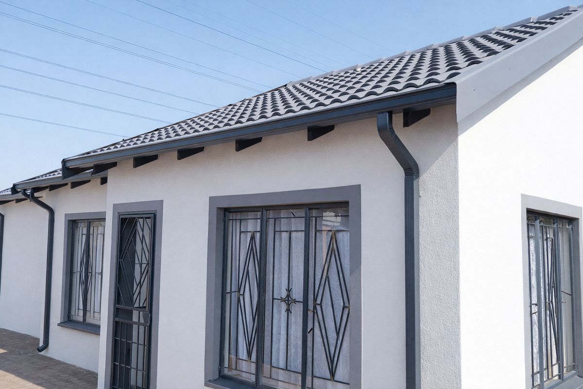 A well-maintained exterior view of the house featuring modern tiled roofing, clean white rendered walls, and secure metal window and door grilles.
