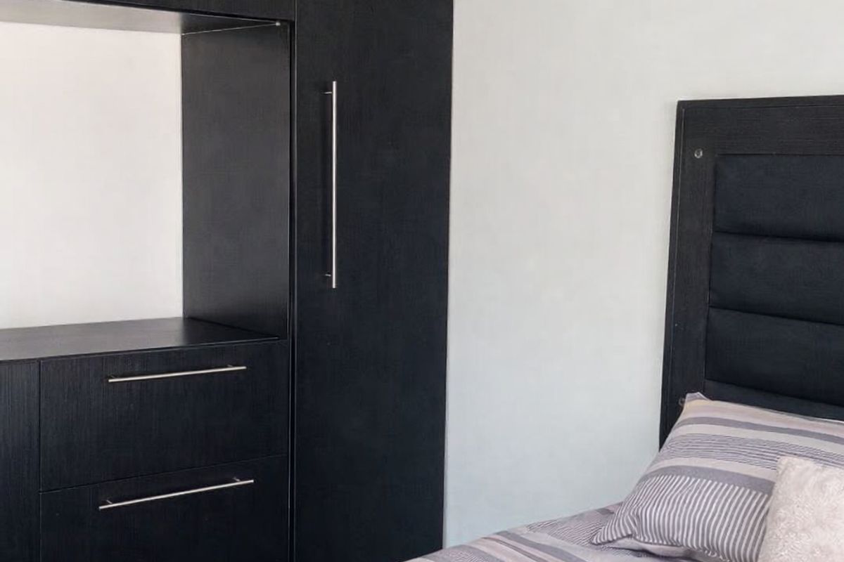 A bedroom featuring built-in dark wood cabinetry with integrated drawers and storage space.