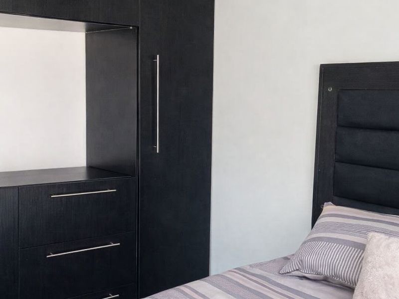 A bedroom featuring built-in dark wood cabinetry with integrated drawers and storage space.