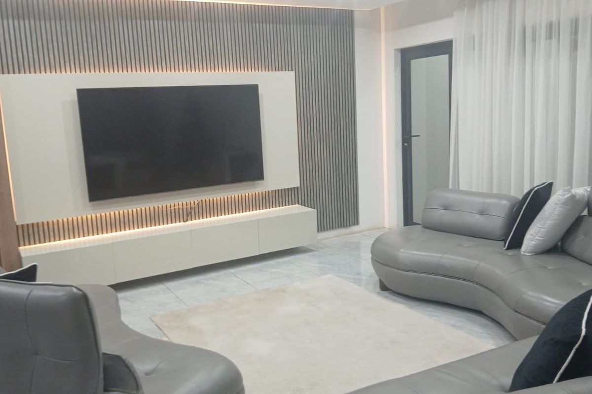 Modern living room featuring a contemporary slatted feature wall with integrated LED lighting, a floating media console, and polished floor tiles.