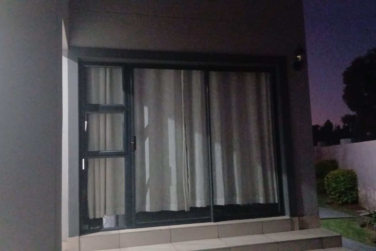 Exterior view of a modern sliding glass door leading to a patio area at dusk.