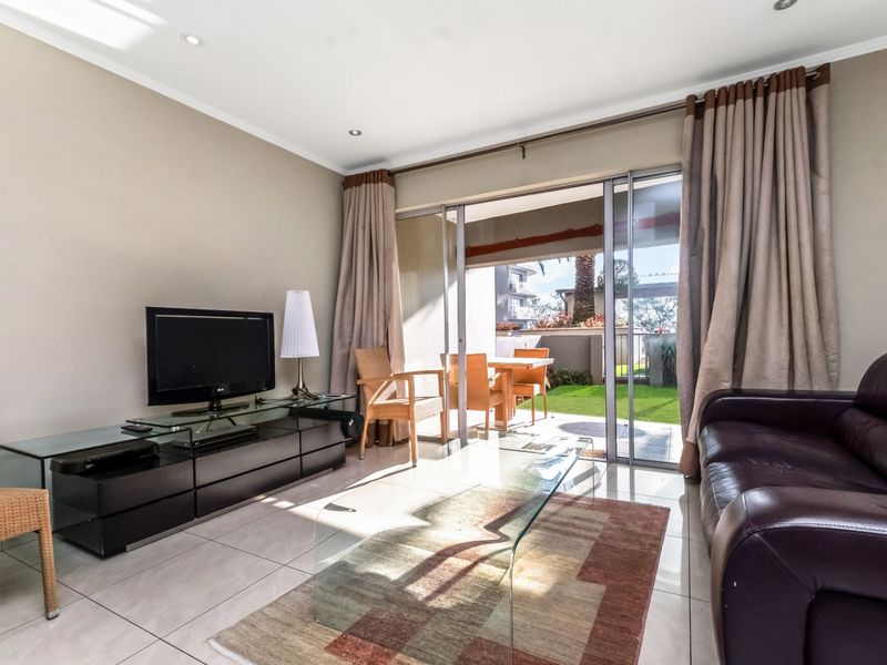 Bright living room featuring large sliding glass doors that open onto a private patio and garden area, providing seamless indoor-outdoor flow.