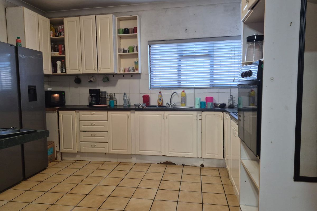 A dated kitchen featuring white cabinetry, dark countertops, tiled flooring, and a built-in oven, offering a functional layout ready for modernization.
