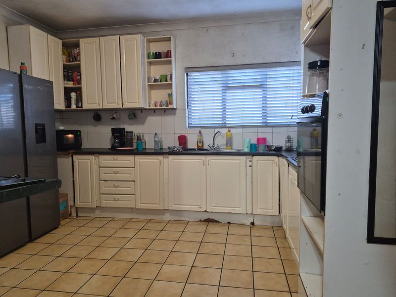 A dated kitchen featuring white cabinetry, dark countertops, tiled flooring, and a built-in oven, offering a functional layout ready for modernization.