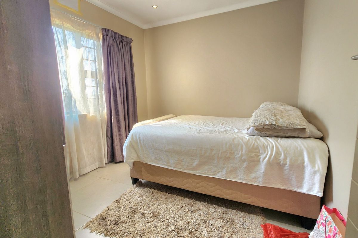 A standard bedroom featuring tiled flooring, neutral wall finishes, and a window with curtain tracks.