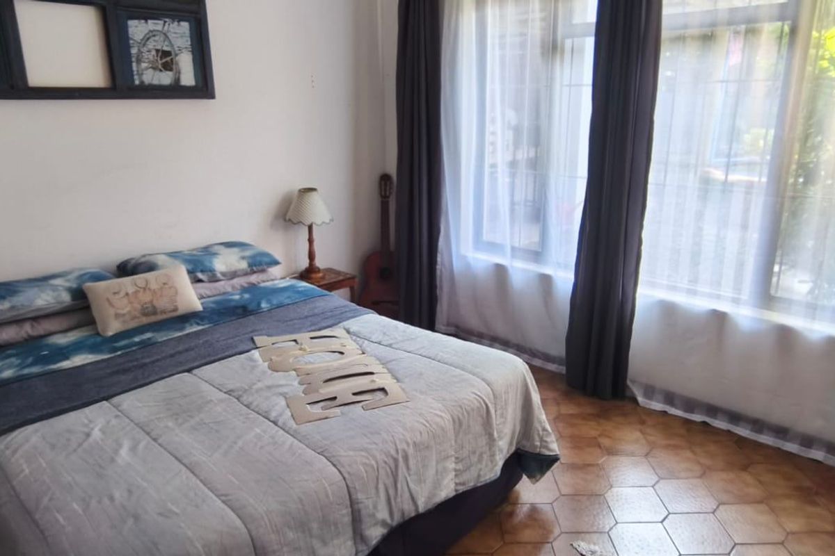 A bedroom featuring large windows with curtains and hexagonal floor tiles.
