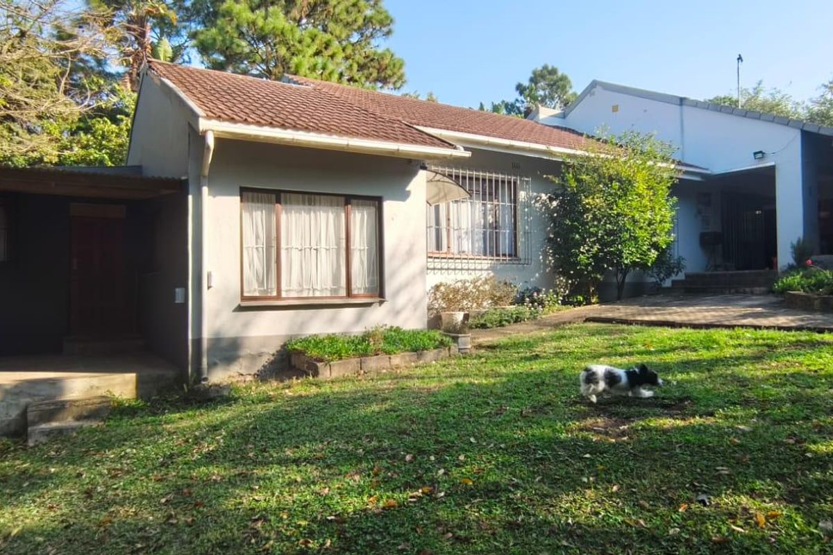 A view of the rear exterior of the house, featuring a tiled roof, covered patio area, and a spacious garden.