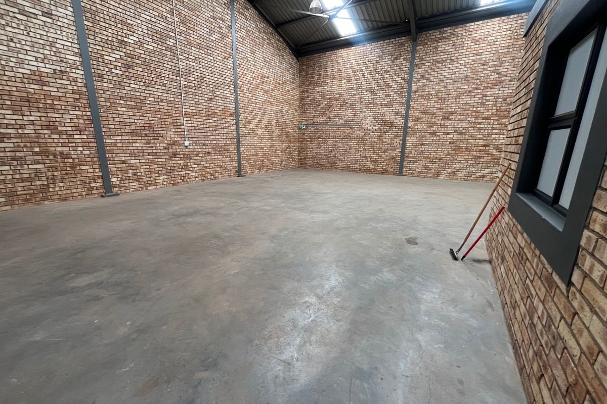 Spacious industrial warehouse unit featuring exposed brick walls, polished concrete flooring, and high-pitched roof with integrated skylights.