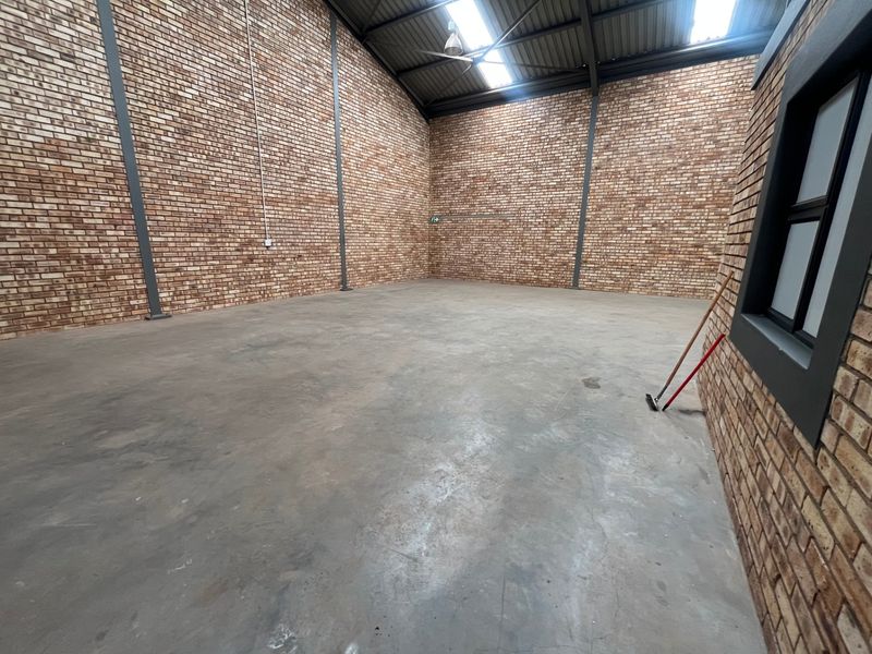 Spacious industrial warehouse unit featuring exposed brick walls, polished concrete flooring, and high-pitched roof with integrated skylights.