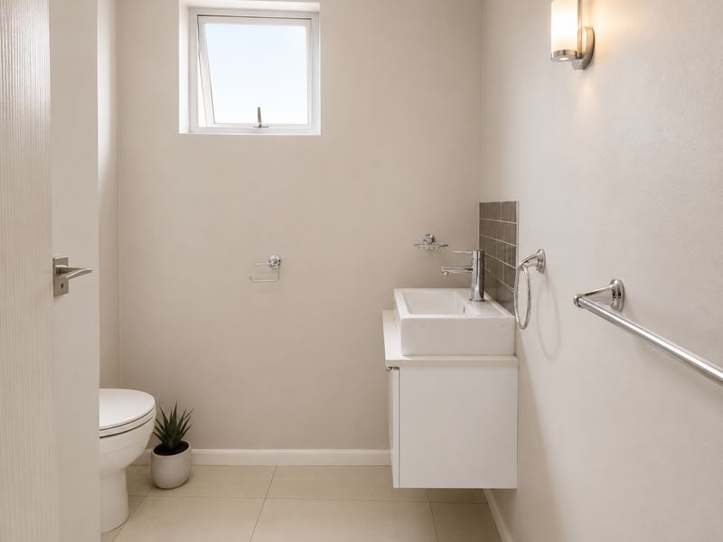 A modern, well-maintained guest bathroom featuring a wall-mounted vanity with a basin, tiled flooring, and neutral wall finishes.
