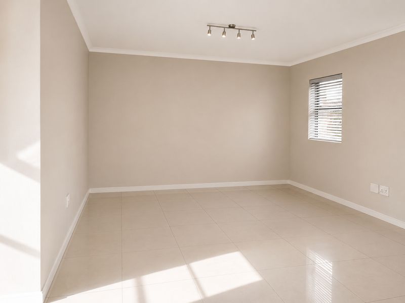 A bright, empty bedroom featuring neutral tiled flooring, clean painted walls, and a modern adjustable spotlight fixture.