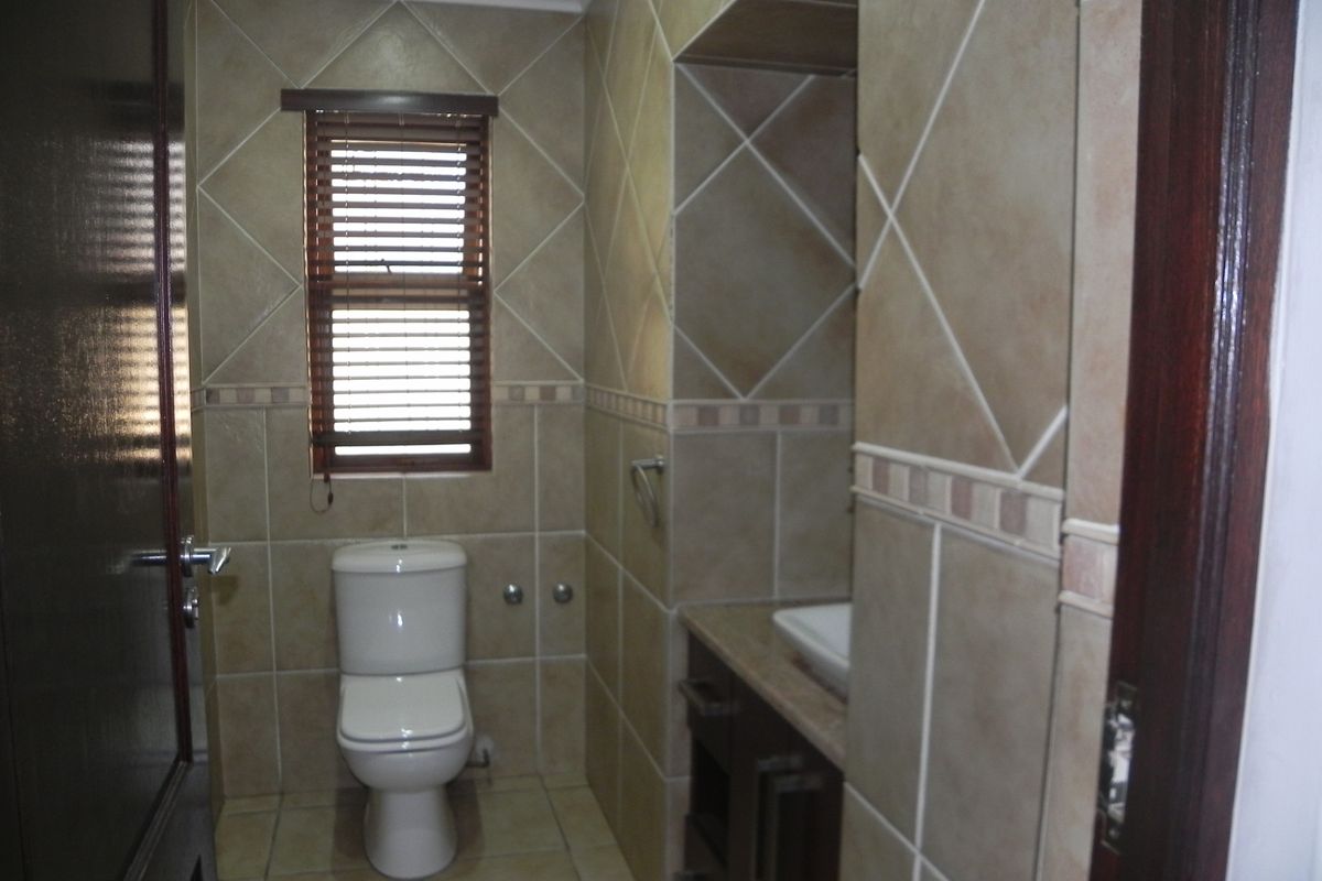A compact bathroom featuring floor-to-ceiling tiled walls, a built-in vanity with a vessel sink, and a standard toilet.